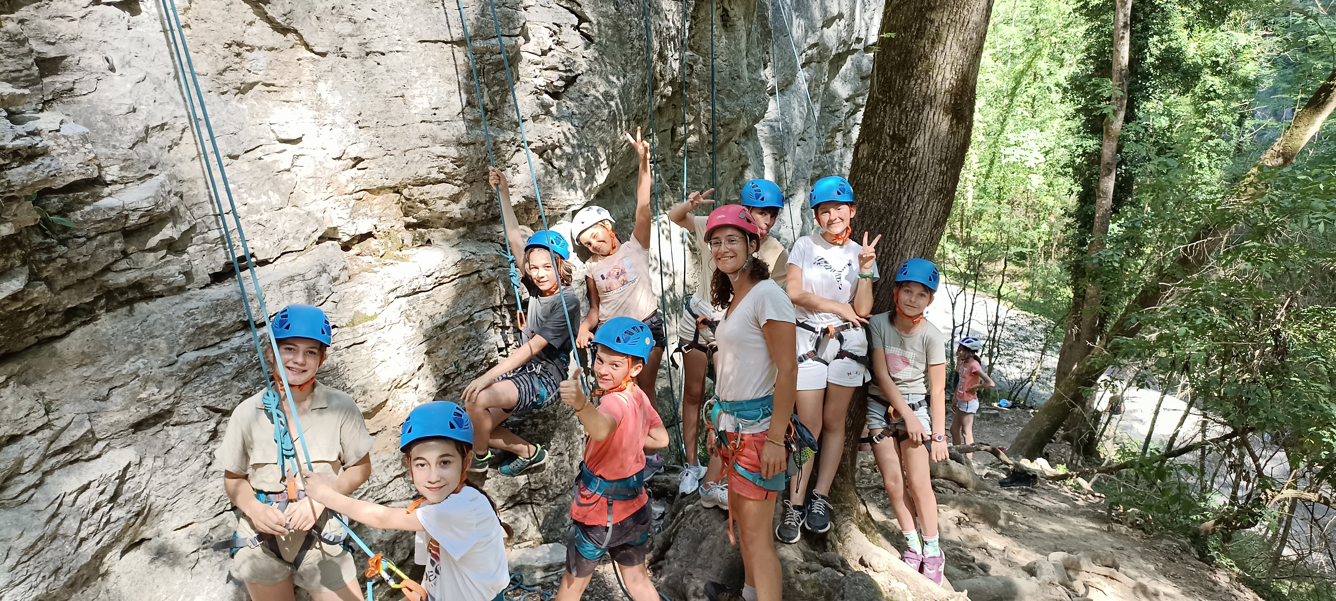 Dora encadrant un groupe d'enfants en escalade extérieure, casques bleus